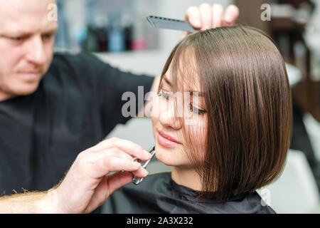 Stylistin ist Frau Haar schneiden und Neue hairdress im Salon. Friseur schneiden client Haare im Schönheitssalon. Frisur und Personen Konzept Stockfoto