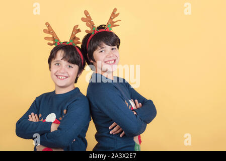Lächelnde Kinder in einem Rudolph Rentier Weihnachten Kostüm auf gelbem Hintergrund Stockfoto