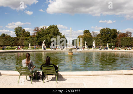 Zwei junge Frauen, die von der Grand Bassin Rond Teich mit Springbrunnen in den Tuilerien an einem Sommertag in Paris, Frankreich. Stockfoto