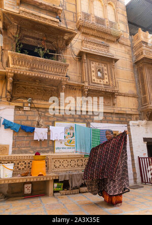 Indische Frau hängenden Saris vor ihr Haveli, Jaisalmer, Rajasthan, Indien Stockfoto