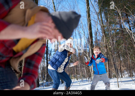 Familie von Mutter, Vater und junge Kind Spaß im Schnee im Winter und das Werfen mit Schneebällen während einer spielerischen Kampf Stockfoto