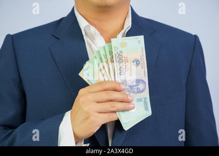 Geld in Vietnam halten an Hand der Mann trägt einen blauen Anzug (Sozialistische Republik Vietnam), Dong, VND, Bezahlung, Geld Vietnamesen auf weißem Bac Stockfoto