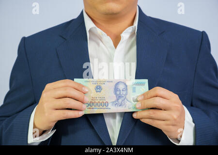 Geld in Vietnam halten an Hand der Mann trägt einen blauen Anzug (Sozialistische Republik Vietnam), Dong, VND, Bezahlung, Geld Vietnamesen auf weißem Bac Stockfoto