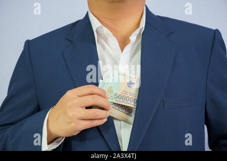 Geld in Vietnam halten an Hand der Mann trägt einen blauen Anzug (Sozialistische Republik Vietnam), Dong, VND, Bezahlung, Geld Vietnamesen auf weißem Bac Stockfoto
