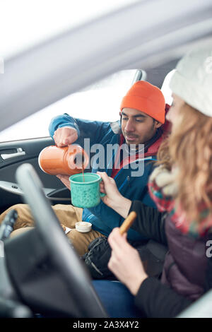 Glücklich, multi-ethnischen Freunde der kaukasischen und indischer Herkunft, die Weihnachten Geschenke und zu Fuß in einer verschneiten Park während der Ferien Stockfoto