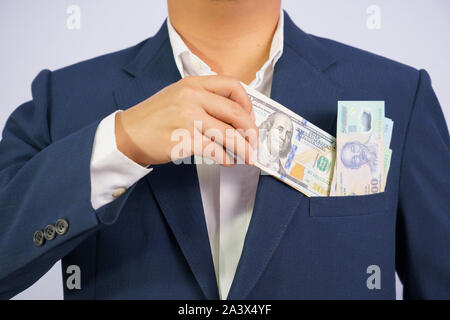 Geld in den USA halten an Hand Geschäftsmann und Geld in Vietnam (VND) halten an Hand der Mann trägt einen blauen Anzug (Sozialistische Republik Vietnam) wearin Stockfoto