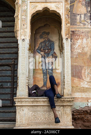 Indische Mann schlafen unter einem Wandbild eines alten haveli, Rajasthan, Nawalgarh, Indien Stockfoto