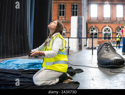 Ein paar riesige Beine als "heimliche" Messung über 10 Meter in der Höhe bekannt sind, errichtet an der Aviva Investors Manchester Art Fair an der Manchester Central über 11.-13. Oktober 2019. Die Beine sind die Arbeit der 23 Jahre alte Manchester School of Art graduate Millie Sansom. Die Installation ist aus Stoff, Polystyrol und Kunstleder und demonstriert das Ungleichgewicht der Machtverteilung zwischen Bürgern und politischen oder Corporate "Riesen". Stockfoto