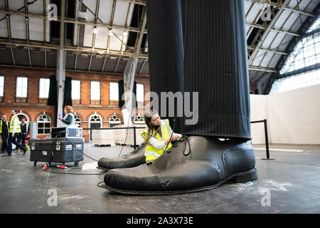 Ein paar riesige Beine als "heimliche" Messung über 10 Meter in der Höhe bekannt sind, errichtet an der Aviva Investors Manchester Art Fair an der Manchester Central über 11.-13. Oktober 2019. Die Beine sind die Arbeit der 23 Jahre alte Manchester School of Art graduate Millie Sansom. Die Installation ist aus Stoff, Polystyrol und Kunstleder und demonstriert das Ungleichgewicht der Machtverteilung zwischen Bürgern und politischen oder Corporate "Riesen". Stockfoto