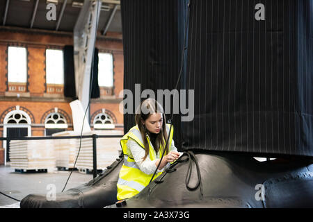 Ein paar riesige Beine als "heimliche" Messung über 10 Meter in der Höhe bekannt sind, errichtet an der Aviva Investors Manchester Art Fair an der Manchester Central über 11.-13. Oktober 2019. Die Beine sind die Arbeit der 23 Jahre alte Manchester School of Art graduate Millie Sansom. Die Installation ist aus Stoff, Polystyrol und Kunstleder und demonstriert das Ungleichgewicht der Machtverteilung zwischen Bürgern und politischen oder Corporate "Riesen". Stockfoto