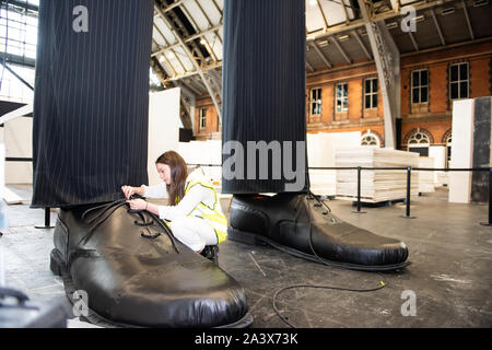 Ein paar riesige Beine als "heimliche" Messung über 10 Meter in der Höhe bekannt sind, errichtet an der Aviva Investors Manchester Art Fair an der Manchester Central über 11.-13. Oktober 2019. Die Beine sind die Arbeit der 23 Jahre alte Manchester School of Art graduate Millie Sansom. Die Installation ist aus Stoff, Polystyrol und Kunstleder und demonstriert das Ungleichgewicht der Machtverteilung zwischen Bürgern und politischen oder Corporate "Riesen". Stockfoto