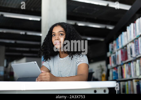 High School afrikanische amerikanische Studentin studieren mit digitalen Tablet in Bibliothek Stockfoto