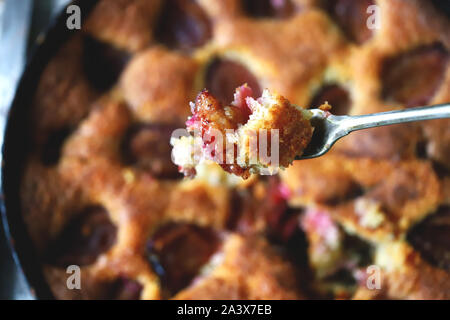 Selektive konzentrieren. Stück Pflaumenkuchen auf eine Gabel. Hausgemachte amerikanische Pflaumenkuchen. Makro. Stockfoto