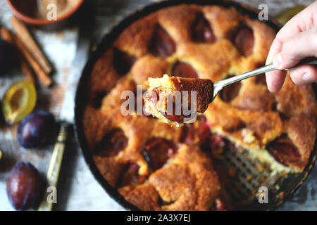 Selektive konzentrieren. Stück Pflaumenkuchen auf eine Gabel. Hausgemachte amerikanische Pflaumenkuchen. Makro. Stockfoto