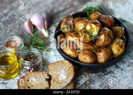 Gebackene Kartoffeln in der Schale in einer gusseisernen Pfanne. Rustikale Kartoffeln. Selektive konzentrieren. Makro. Stockfoto