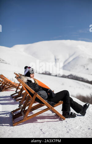Junge Frau Skifahrer entspannen in einem Sessel nach dem Skifahren in den Bergen im Winter Stockfoto