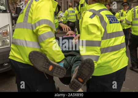 Trafalgar Square, London, Großbritannien. Oktober 2019. Polizeibeamte entführen einen Aktivisten der Extinction Rebellion während der Internationalen Rebellion im Oktober 2019 am Trafalgar Square in London. Der Aktivist wird im Rahmen einer koordinierten Aktion zur Räumung des Protestortes festgenommen. Penelope Barritt/Alamy Live News Stockfoto
