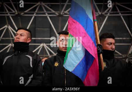 10. Oktober 2019, Ecuador, Quito: Drei Polizisten festgenommen, die von indigenen Völkern stehen auf einer Stufe mit einem indigenen Flagge. Die kugelsichere Westen wurden ihnen genommen. Durch diese Aktion, indigene Menschen wollen, dass die Regierung davon zu überzeugen, ihren Übergang in die Nationalversammlung zu genehmigen. Fast 20.000 ecuadorianischen Indigenas marschierten auf den Straßen von Quito, der Tag vor. Sie protestierten gegen Diesel immer 120 Prozent teurer. Nach offiziellen Angaben fünf Menschen bei den Protesten ums Leben. Foto: Juan Diego Montenegro/dpa Stockfoto