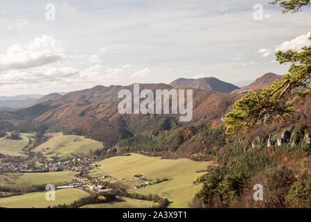 Sulov-Hradna Dorf mit teilweise felsigen Hügeln von Sulovske vrchy von bunten Wald bedeckt in der Slowakei im Herbst Stockfoto