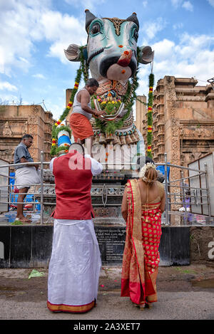 Madurai, Indien - August 23, 2018: Ein paar Vor Nandi Statue zu beten. Nandi ist der heilige Stier Kalb, Gatekeeper, und dem Fahrzeug der Gott Shiva Stockfoto