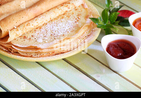 Close-up frischen hausgemachten gerollt Crepes auf gelbem Teller mit Erdbeeren Marmelade auf hölzernen Tisch Stockfoto