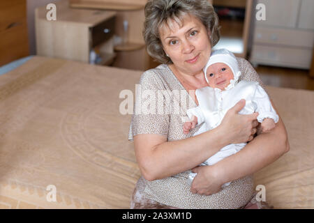 Kleiner Junge in den Armen der Großmutter zu Hause Stockfoto