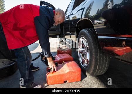 Oktober 10, 2019, Big Oak Flat/Groveland, Kalifornien, USA: Big Oak Flat Bewohner, Ken Lawrence, füllt Benzin Behälter im Mart Tankstelle der Bergmann in der Nähe seiner Wohnung am Donnerstag Morgen. Er wird das Gas für seine home Generator während der aktuellen PG&E herunterfahren zu verwalten. Lawrence sagte, er spricht auf der ham Radio und die allgemeine Meinung mit anderen Schinken Betreiber ist die Abschaltung ist nicht sehr beliebt. Er glaubt, daß die Abschaltung wegen sehr schlechter Planung auf PG&E Teil ist. Zum Schutz der öffentlichen Sicherheit, PG&E ausgeschaltet hat Strom auf ca. 34.400 Kunden in Tuolumne County aufgrund gusty Win Stockfoto