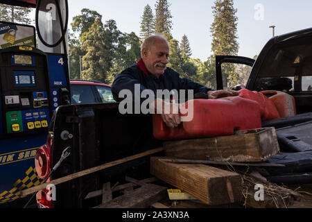 Oktober 10, 2019, Big Oak Flat/Groveland, Kalifornien, USA: Big Oak Flat Bewohner, Ken Lawrence, Lasten voll Benzin Behälter in seinen Lkw Donnerstag Morgen an Mart Tankstelle der Bergmann in der Nähe seiner Wohnung. Er wird das Gas für seine home Generator während der aktuellen PG&E herunterfahren zu verwalten. Lawrence sagte, er spricht auf der ham Radio und die allgemeine Meinung mit anderen Schinken Betreiber ist die Abschaltung ist nicht sehr beliebt. Er glaubt, daß die Abschaltung wegen sehr schlechter Planung auf PG&E Teil ist. Zum Schutz der öffentlichen Sicherheit, PG&E ausgeschaltet hat Strom auf ca. 34.400 Kunden in Tuolumne County Stockfoto