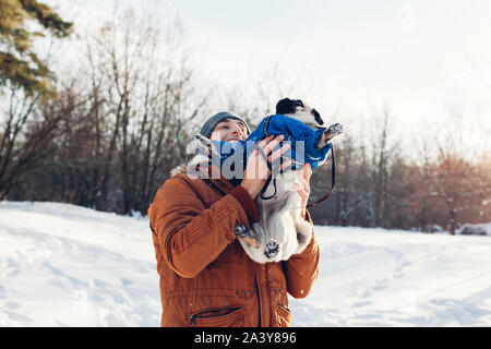 Mops Hund wandern mit seinem Meister. Mann spielt mit seinem Haustier und Spaß haben. Welpen tragen Winter Mantel. Stockfoto