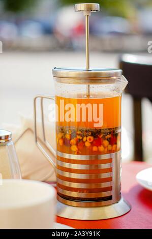 Vitaminic gesunde orange Koffein frei Sanddorn Tee in der französischen Presse mit frischen, rohen Sanddornbeeren. Stockfoto