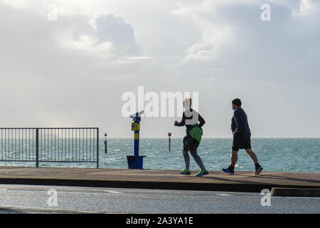 Im mittleren Alter der männlichen und weiblichen Läufern Jogging entlang der Promenade am Meer Stockfoto