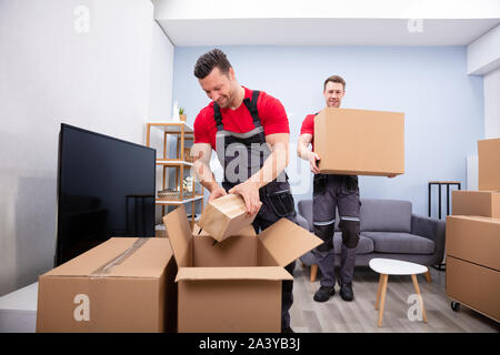 Zwei junge Movers in Uniform Kommissionierung und das Inverkehrbringen von Produkten in der Kartons Stockfoto