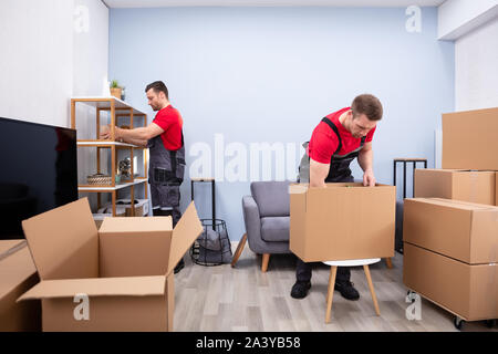 Zwei junge Movers in Uniform Kommissionierung und das Inverkehrbringen von Produkten in der Kartons Stockfoto