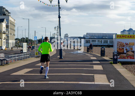 Ein Mann in helle Kleidung Laufen oder Joggen am Strand Stockfoto