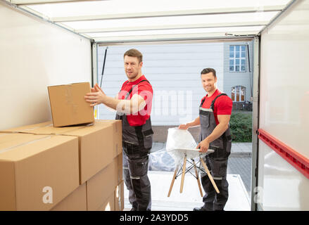 Portrait von Lächelnden jungen männlichen Movers die Produkte Anordnen in Van Stockfoto