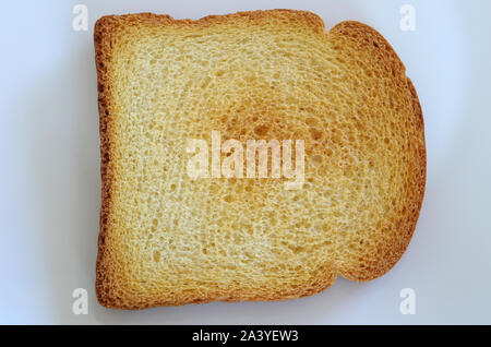 Eine Nahaufnahme von einer knusprigen Scheibe Toast Brot auf eine weiße Platte, bereit für Frühstück oder eine andere Mahlzeit. Stockfoto