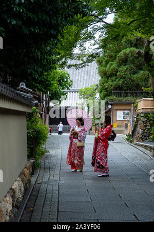 Zwei schöne japanische Frauen tragen traditionelle Sommer Kimonos (bunte Yukatas) mit einem rosa Papier Sonnenschirm, Haken Bilder mit ihrem Smartphone. Stockfoto