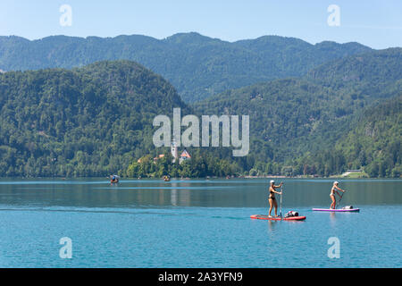 Blick auf die Insel und Frauen paddleboarding, der See von Bled, Bled, Obere Kraina, Slowenien Stockfoto