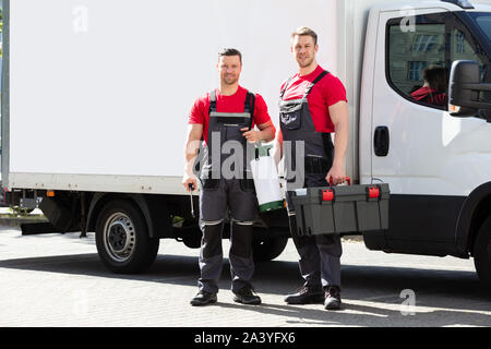 Porträt eines lächelnden Techniker gegen die Lkw-Holding Tool Box In Händen stehend Stockfoto