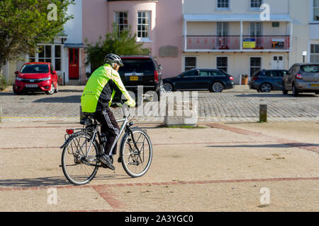 Ein Mann mittleren Alters Radfahren tragen Gut sichtbare Kleidung und einen Velohelm Stockfoto