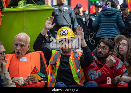 New York City, USA. 10 Okt, 2019. Klima Aktivisten angeschlossen mit der globalen Umwelt Gruppe? Aussterben Rebellion' inszeniert eine gewaltfreie Akt zivilen Ungehorsams' in der Mitte des Times Square, Sperrung des Verkehrs für etwa eine Stunde. Die Demonstranten ein Lime Green Boot an der Kreuzung von Broadway und 44th Street geparkt, das Schiff umgeben und fuhr fort, sich Kette zu Sekundenkleber. Entsprechend der NYPD, 62 Demonstranten wurden festgenommen. (Foto von Michael Nigro/Pacific Press) Quelle: Pacific Press Agency/Alamy leben Nachrichten Stockfoto