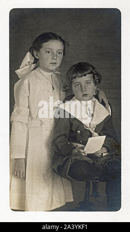 Ein Junge und ein Mädchen, Geschwister, um 1910 in dress up posieren. Kleiner Junge trägt ein matrosenanzug und der älteren Schwester in einem weißen Lacey Kleid. Stockfoto