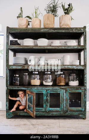 Junge versteckt sich im Schrank in der Küche Stockfoto