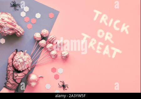 Creative Paper Craft Halloween flach auf Rosa und Grau split Papier Hintergrund mit den Augen und der Spinnen. Hände in schwarz Stechschutzhandschuhe holding Dekorationen. Stockfoto