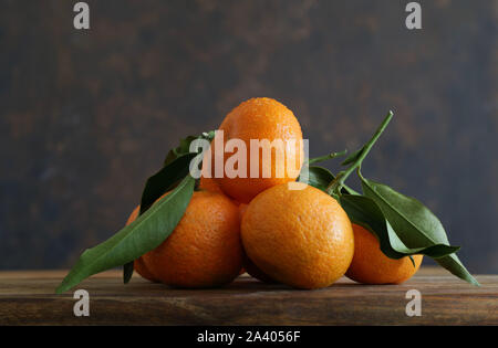 In der Nähe von vielen frischen Mandarinen mit Blättern auf hölzernen Tisch Stockfoto