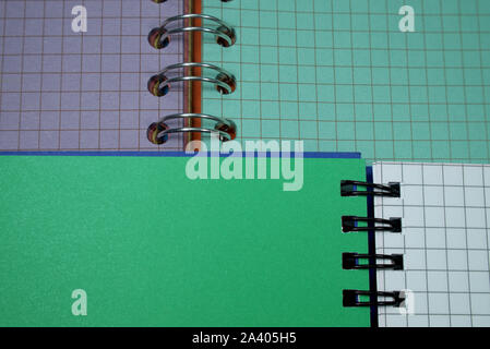 Kabel gebunden öffnen Notebook entschieden mit Plätzen liegen auf einem zweiten offenen Notebook mit Grün und Lila Seiten in einem konzeptionellen Bild für Business oder educatio Stockfoto