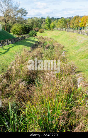 Eine Bewässerung Entwässerungskanal mit Schilf und Vegetation in einem wilden Park auf einem Hügel bewachsen. Schäden durch nicht rechtzeitige Wartung Stockfoto