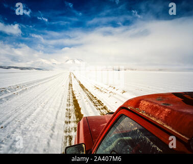 Rot Jeep entlang einer Schnee-bedeckten Pfad auf dem Altiplano in Bolivien Stockfoto