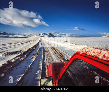 Rot Jeep entlang einer Schnee-Pfad auf dem Altiplano in Bolivien, mit Bergen im Hintergrund Stockfoto