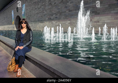 Frau sitzt auf der Kante eines Brunnen vor der Nationalgalerie von Victoria nach dem Besuch der Vincent Van Gogh Ausstellung. Stockfoto